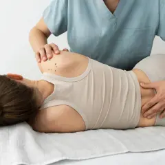 Fizjoterapeuta delikatnie uciska plecy pacjentki, pomagając złagodzić objawy dyskopatii.