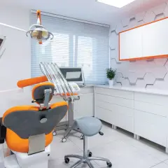 Nowoczesny gabinet stomatologiczny z fotelem, unitem i szafkami.