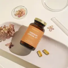 Butelka suplementu Omega-3 z 250 mg DHA, obok kapsułki i suszone kwiaty.