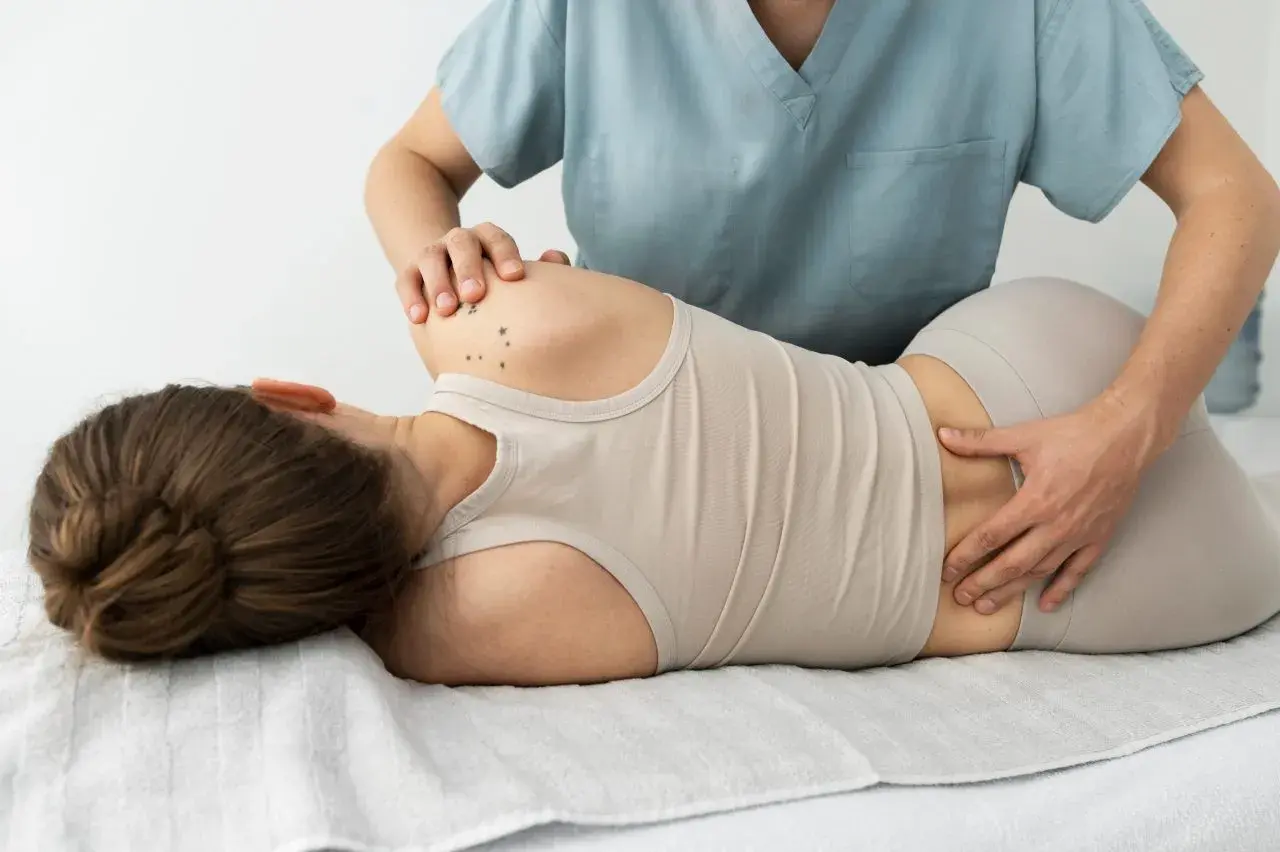 Fizjoterapeuta delikatnie uciska plecy pacjentki, pomagając złagodzić objawy dyskopatii.