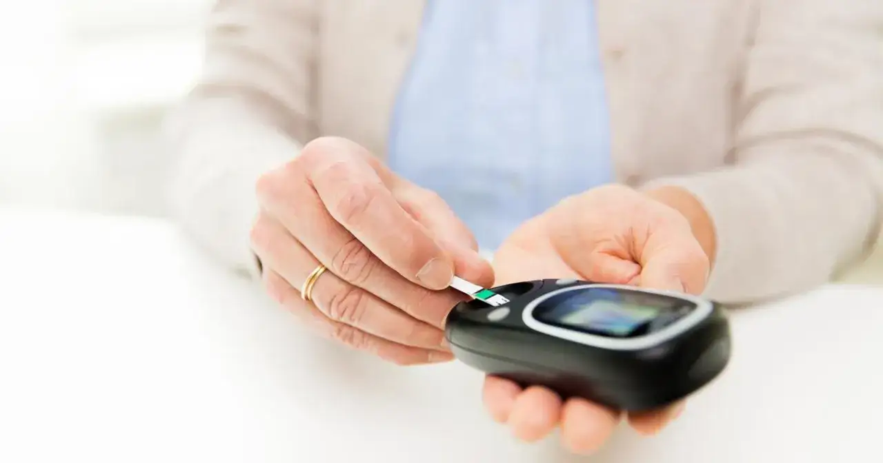 Osoba z pierścionkiem na palcu wkłada pasek do glukometru. To ważny element kontroli cukrzycy, o którym radzi diabetolog.